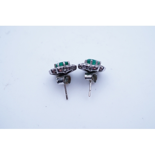 294 - A pair of emerald and diamond earrings, each of cluster design, set with an oval emerald within a mi... 