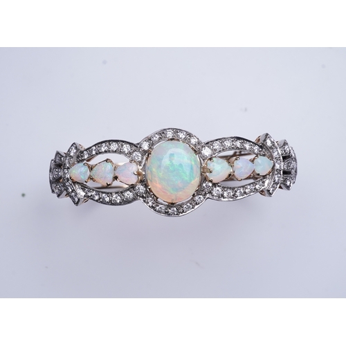 308 - An opal and diamond bangle, of hinged design, the front set with cabochon and heart-shaped opals wit... 