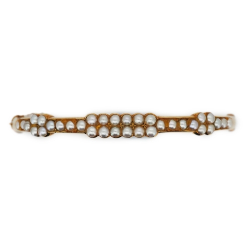 318 - An Edwardian seed pearl bangle, early 20th century, of hinged design, set to the front with half see... 