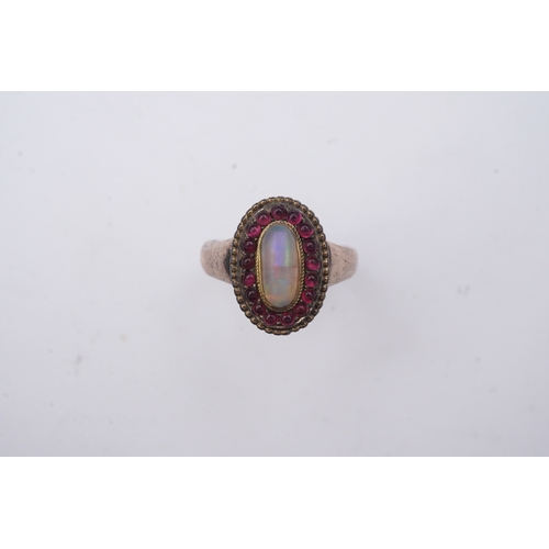 338 - An opal and garnet ring, of cluster design, set with an oval cabochon opal within a border of caboch... 