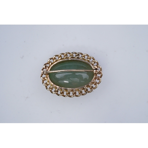 343 - A 9ct gold and jadeite brooch, set with a cabochon jadeite, within a curb link outer border in 9ct g... 