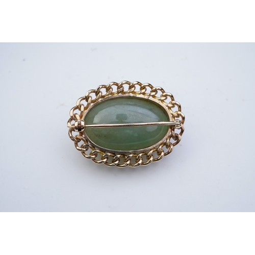 343 - A 9ct gold and jadeite brooch, set with a cabochon jadeite, within a curb link outer border in 9ct g... 