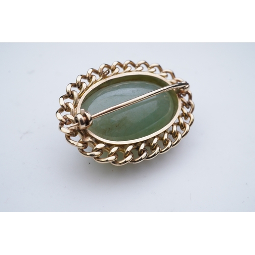 343 - A 9ct gold and jadeite brooch, set with a cabochon jadeite, within a curb link outer border in 9ct g... 