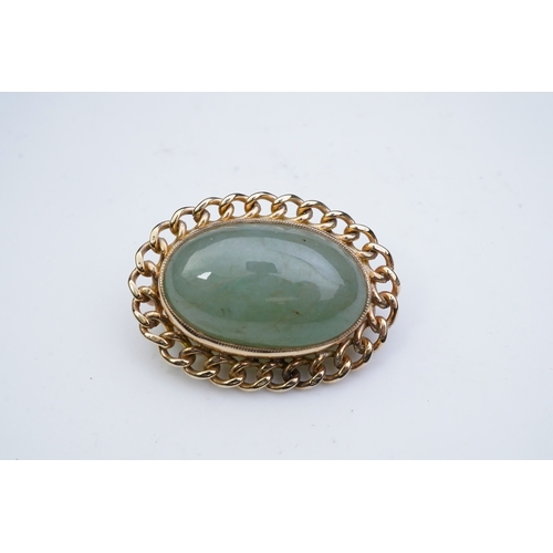 343 - A 9ct gold and jadeite brooch, set with a cabochon jadeite, within a curb link outer border in 9ct g... 