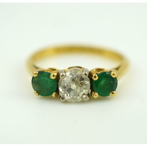 360 - An emerald and diamond three-stone ring, claw-set with a circular-cut diamond weighing approximately... 