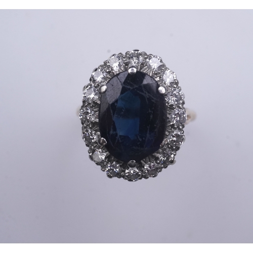 367 - A sapphire and diamond ring, of cluster design, claw-set with an oval deep blue/green sapphire weigh... 