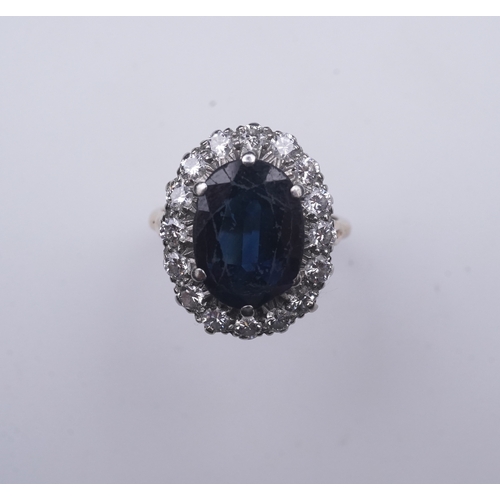 367 - A sapphire and diamond ring, of cluster design, claw-set with an oval deep blue/green sapphire weigh... 