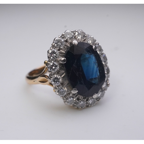 367 - A sapphire and diamond ring, of cluster design, claw-set with an oval deep blue/green sapphire weigh... 