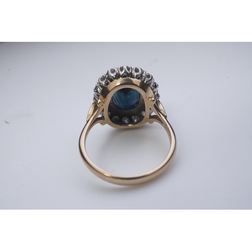 367 - A sapphire and diamond ring, of cluster design, claw-set with an oval deep blue/green sapphire weigh... 