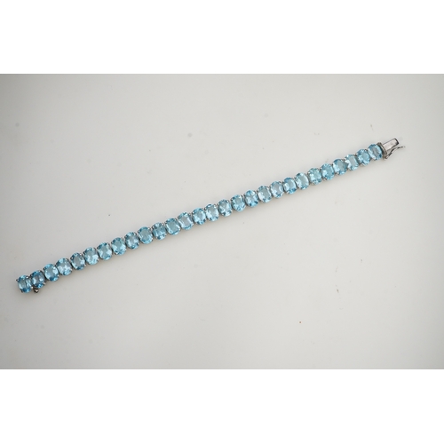 398 - A blue topaz bracelet, designed as an articulated line of oval blue topazes, mounted in silver, leng... 