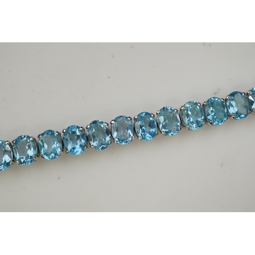 398 - A blue topaz bracelet, designed as an articulated line of oval blue topazes, mounted in silver, leng... 