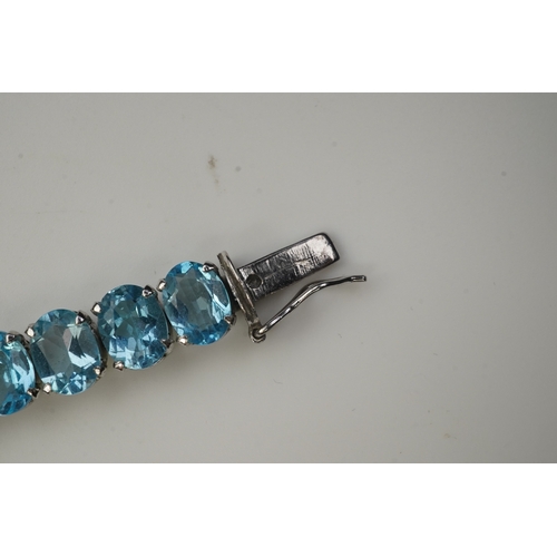 398 - A blue topaz bracelet, designed as an articulated line of oval blue topazes, mounted in silver, leng... 