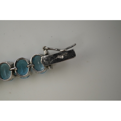 398 - A blue topaz bracelet, designed as an articulated line of oval blue topazes, mounted in silver, leng... 