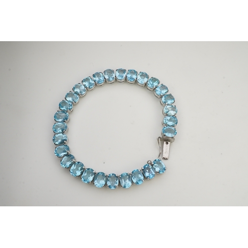 398 - A blue topaz bracelet, designed as an articulated line of oval blue topazes, mounted in silver, leng... 