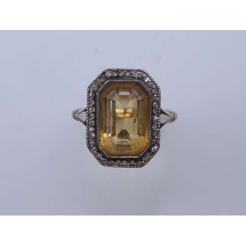 414 - A citrine and diamond ring, early 20th century, set with a step-cut citrine within a border of rose-... 