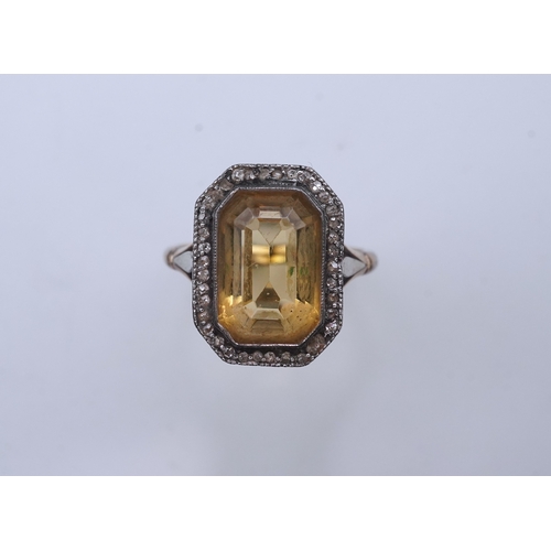 414 - A citrine and diamond ring, early 20th century, set with a step-cut citrine within a border of rose-... 