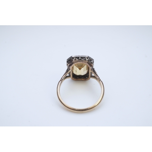 414 - A citrine and diamond ring, early 20th century, set with a step-cut citrine within a border of rose-... 