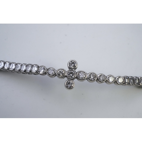 421 - A diamond bracelet, designed as a sequence of links set with step-cut diamonds, centring on a cross ... 