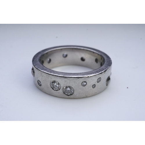 423 - A platinum and diamond eternity ring, set with a continuous band of scattered brilliant-cut diamonds... 