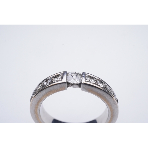 426 - A diamond eternity ring, centring on a tension-set circular-cut diamond weighing approximately 0.25 ... 