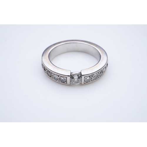 426 - A diamond eternity ring, centring on a tension-set circular-cut diamond weighing approximately 0.25 ... 