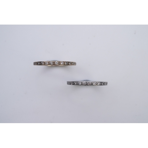 427 - A pair of diamond eternity rings, each set a continuous band of brilliant-cut diamonds, mounted in y... 