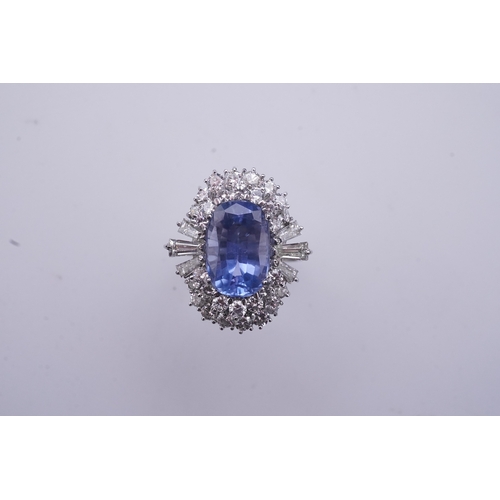 433 - A sapphire and diamond ring, of cluster design, set with an oval sapphire weighing approximately 5.0... 