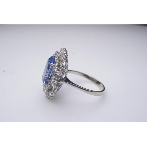 433 - A sapphire and diamond ring, of cluster design, set with an oval sapphire weighing approximately 5.0... 