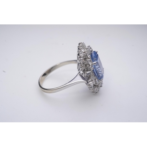 433 - A sapphire and diamond ring, of cluster design, set with an oval sapphire weighing approximately 5.0... 