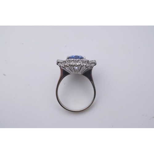 433 - A sapphire and diamond ring, of cluster design, set with an oval sapphire weighing approximately 5.0... 