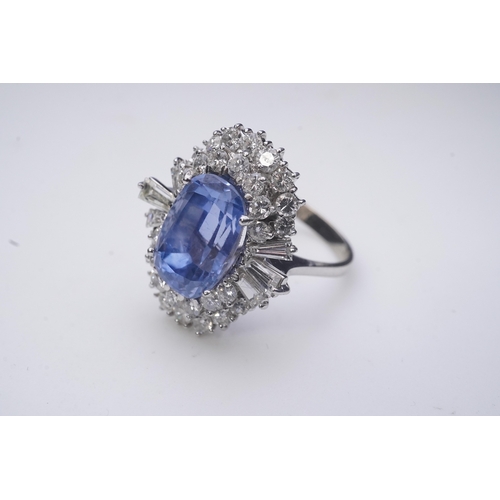 433 - A sapphire and diamond ring, of cluster design, set with an oval sapphire weighing approximately 5.0... 