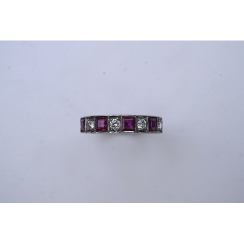 439 - A ruby and diamond half eternity ring, set to the front with a band of step-cut rubies and brilliant... 