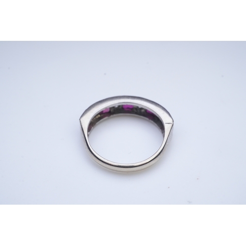 439 - A ruby and diamond half eternity ring, set to the front with a band of step-cut rubies and brilliant... 