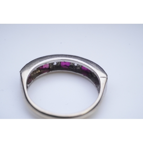 439 - A ruby and diamond half eternity ring, set to the front with a band of step-cut rubies and brilliant... 