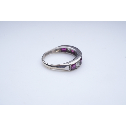 439 - A ruby and diamond half eternity ring, set to the front with a band of step-cut rubies and brilliant... 