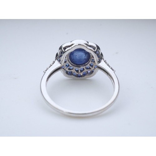 453 - A sapphire ring, of Art Deco inspiration, set with a cabochon sapphire within a floral double border... 