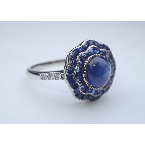 453 - A sapphire ring, of Art Deco inspiration, set with a cabochon sapphire within a floral double border... 