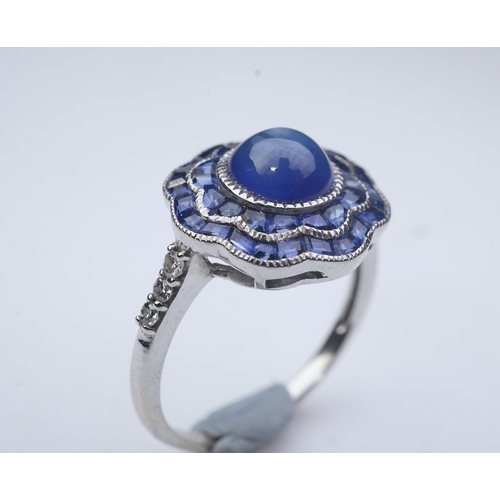 453 - A sapphire ring, of Art Deco inspiration, set with a cabochon sapphire within a floral double border... 