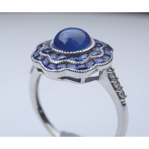 453 - A sapphire ring, of Art Deco inspiration, set with a cabochon sapphire within a floral double border... 