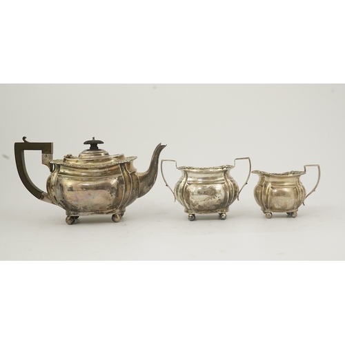 58 - An Edwardian silver three piece tea set, by Thomas Hayes, of rounded rectangular form, with shell an... 