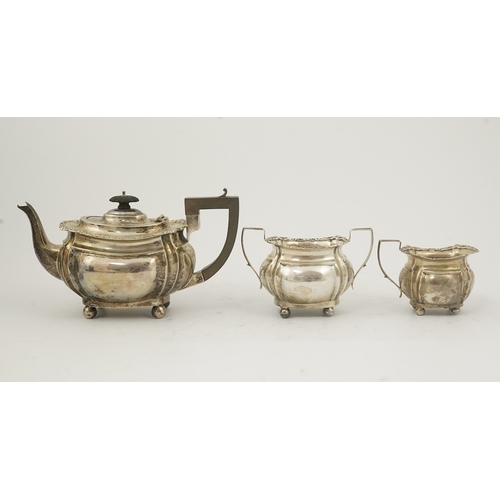 58 - An Edwardian silver three piece tea set, by Thomas Hayes, of rounded rectangular form, with shell an... 