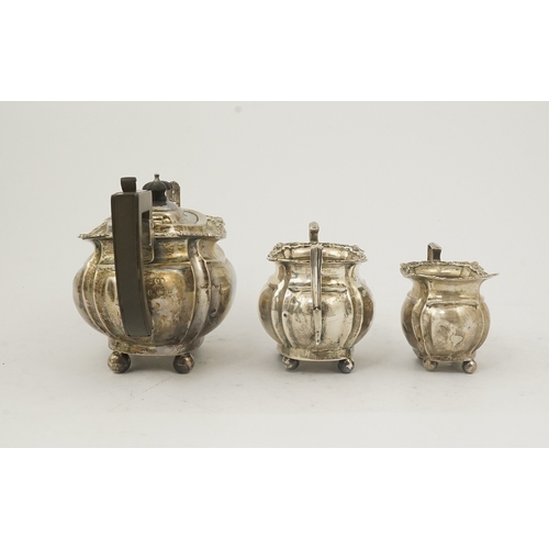 58 - An Edwardian silver three piece tea set, by Thomas Hayes, of rounded rectangular form, with shell an... 