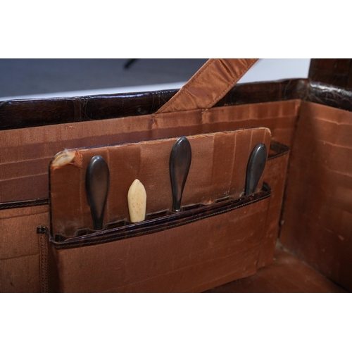 77 - A George V crocodile skin travelling toilet case, containing twelve silver and tortoiseshell mounted... 