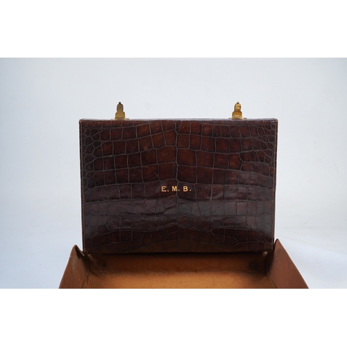 77 - A George V crocodile skin travelling toilet case, containing twelve silver and tortoiseshell mounted... 