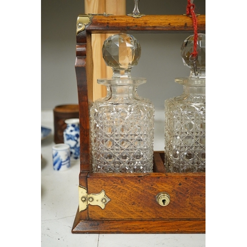 1374 - A brass mounted two bottled oak tantalus, 24cm wide, 33cm high. Condition - fair to good