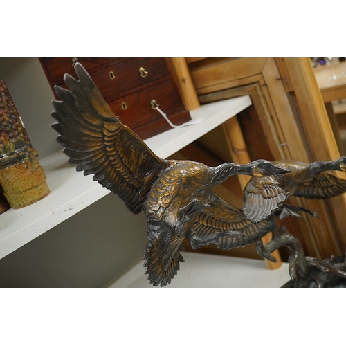 1398 - A modern large cast bronze sculpture of two flying geese, on an oval plinth, 90cm wide. Condition - ... 