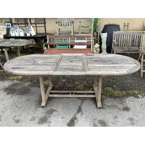 79 - A weathered teak oval extending garden table, width 239cm extended, depth 109cm, height 73cm togethe... 