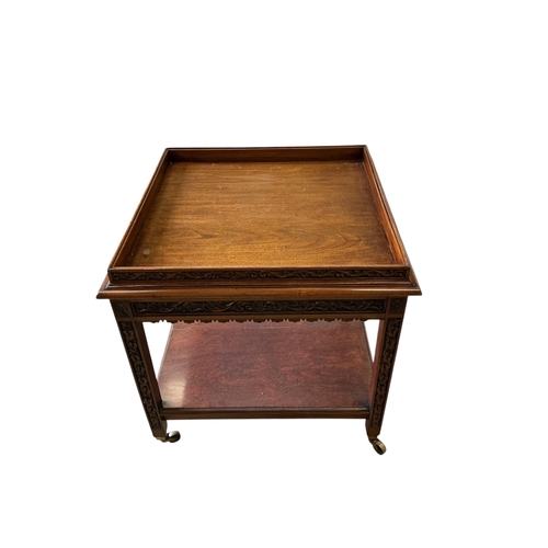 60 - An early 20th century carved walnut square two tier occasional table, with brass caps and casters, 7... 