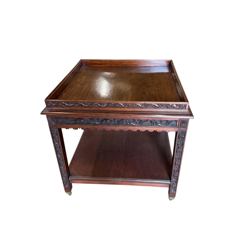 60 - An early 20th century carved walnut square two tier occasional table, with brass caps and casters, 7... 