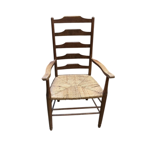 1085 - A pair of Arts & Crafts oak ladderback rush seat elbow chairs, width 62cm, depth 47cm, height 108cm... 